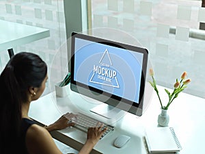 Female office worker working with mock up computer on simple working table
