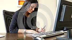 Female office worker writing and signing check