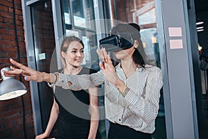 Female office workers having fun at work watching 3d video in VR goggles, woman touching something experiencing virtual