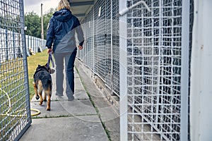 Female officer with detection dog walking by locked cages