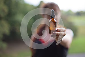 Female with an oil bottle in her hand, gesturing toward the camera