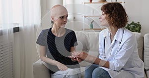 Female oncology nurse practitioner strokes hand of cancer patient