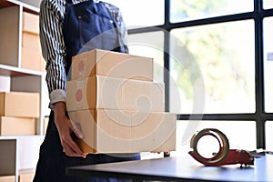 A female online shop owner or worker holding a parcel boxes or cardboard boxes. cropped image