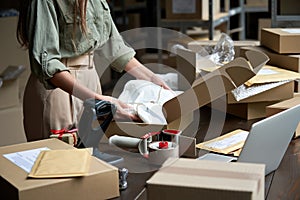 Female online store business owner packing ecommerce shipping box.