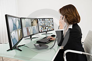 Female Operator Looking At Multiple Camera Footage On Computers