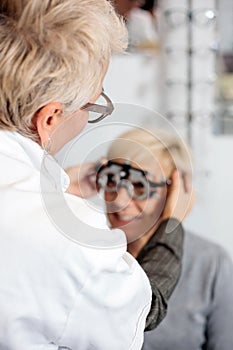 Female ophthalmologist examining mature woman at the ophthalmology clinic, determining diopter