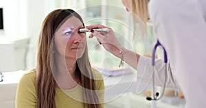 Female ophthalmologist examining pupils of woman patient