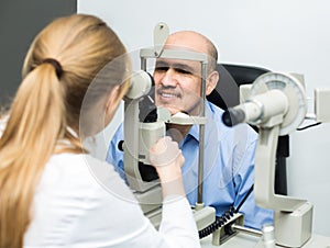 Female ophthalmologist and mature patient checking eyesight in c