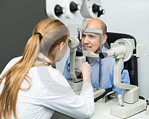 Female ophthalmologist and mature patient checking eyesight in clinic