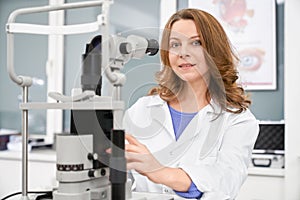 Female ophthalmologist posing with eye test machine.