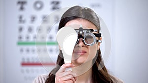 Female in optical trial frame closing eye and squeezing, poor vision problems