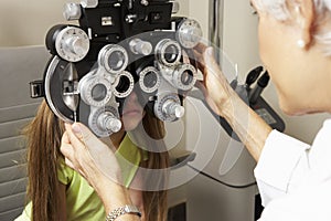 Female Optician In Surgery Giving Girl Eye Test