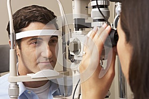 Female Optician In Surgery Giving Man Eye Test