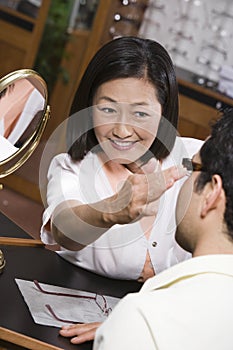 Female Optometrist Assisting Patient In Choosing Spectacles