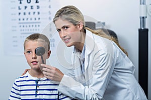 Female optometrist examining young patient with medical equipment