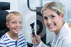 Female optometrist examining young patient with ophthalmoscope