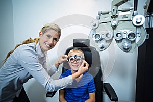 Female optometrist examining young patient with phoropter