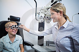 Female optometrist examining young patient with phoropter