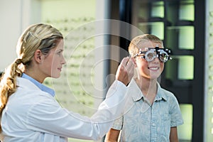 Female optometrist examining young patient with phoropter