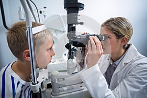 Female optometrist examining young patient on slit lamp