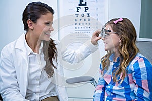 Female optometrist examining young patient with trial frame