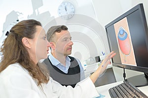 Female optometrist showing eye draft to male patient