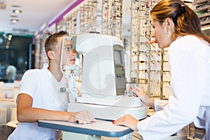 Female optometrist testing eyesight of boy