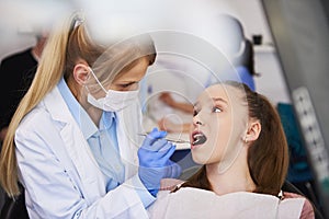 Female orthodontist examining child`s teeth