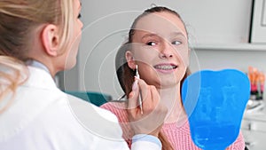 Female orthodontist examining child`s teeth in dentist`s office