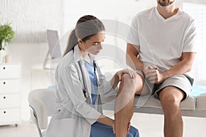 Female orthopedist examining patient`s leg in clinic photo