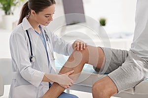 Female orthopedist examining patient`s leg in clinic