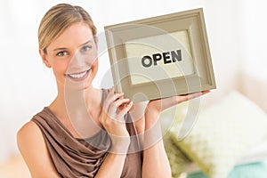 Female Owner Holding Framed Open Sign In Bedding Store