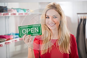 Female Owner Holding Open Sign In Clothing Store