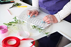 Female owner of a small flower shop orders goods from an online wholesaler