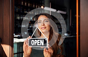 Female Owner Of Start Up Coffee Shop Or Restaurant Turning Round Open Sign On Door photo