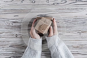 Female packing gifts. Cardboard box in craft paper, christmas rope and tree on the rustic wood planks background.