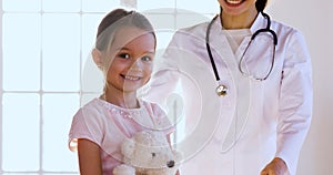 Female paediatrician embrace happy cute child girl look at camera