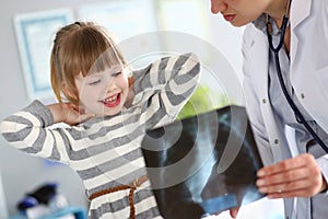 Female paediatrician working with cute little girl at her office explaining diagnosis