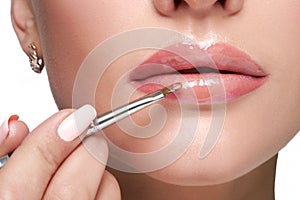 Female paint her lips by cosmetic brush lipstick on lips