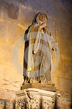 Female painted statue of Christian Saint in golden church light