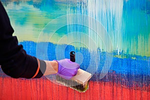 Female painter hand drawing abstract oil painting holding wide brush, painting on colorful canvas