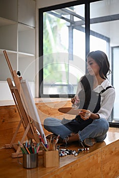 Female painter painting on easel in her studio.