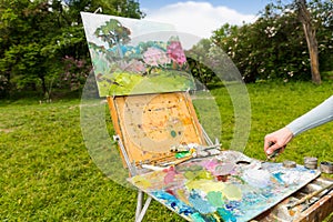 Female painter's hand working with paletteknife outdoors