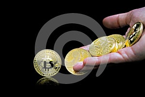 Female hand throws gold bitcoin. bitcoins on a black background. Bitcoins and New Virtual money concept. Bitcoin is a new currency