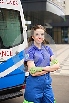 Female paramedic stands on the street near an ambulance
