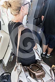 Female passenger carrying the hand luggage bag, walking the airplane boarding corridor.