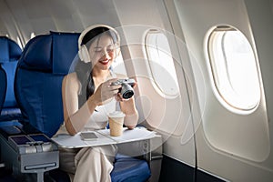 A female passenger is checking pictures on her camera during the flight of her summer vacation