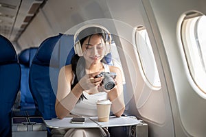 A female passenger is checking pictures on her camera during the flight of her summer vacation