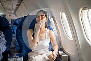 A female passenger is feeling tired and sleepy during a long flight, while traveling by plane