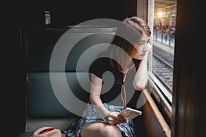 Female passenger listening music traveling by train looking out